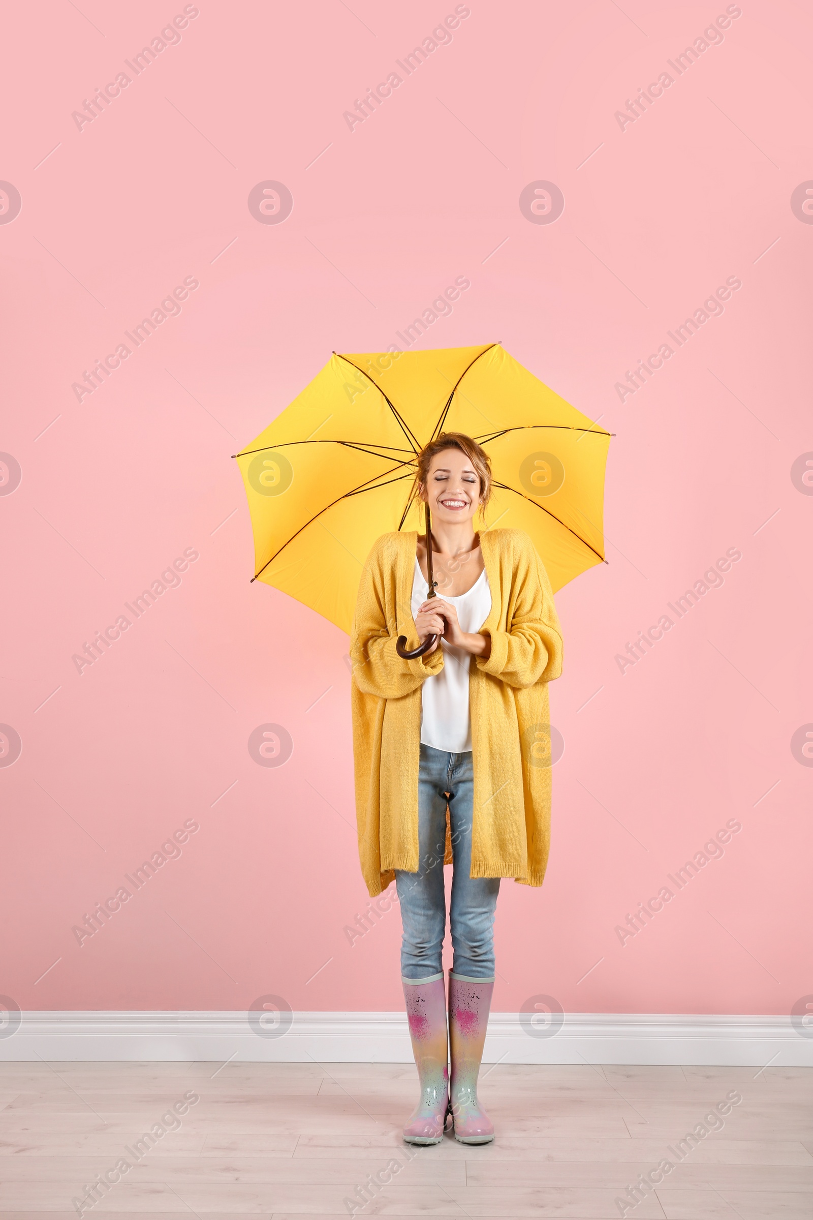 Photo of Woman with yellow umbrella near color wall