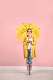 Photo of Woman with yellow umbrella near color wall