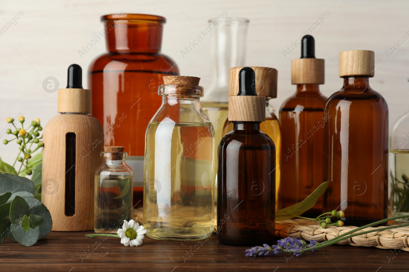 Photo of Aromatherapy. Different essential oils, eucalyptus leaves and flowers on wooden table