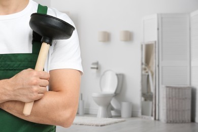 Image of Plumber holding plunger in bathroom, closeup. Space for text