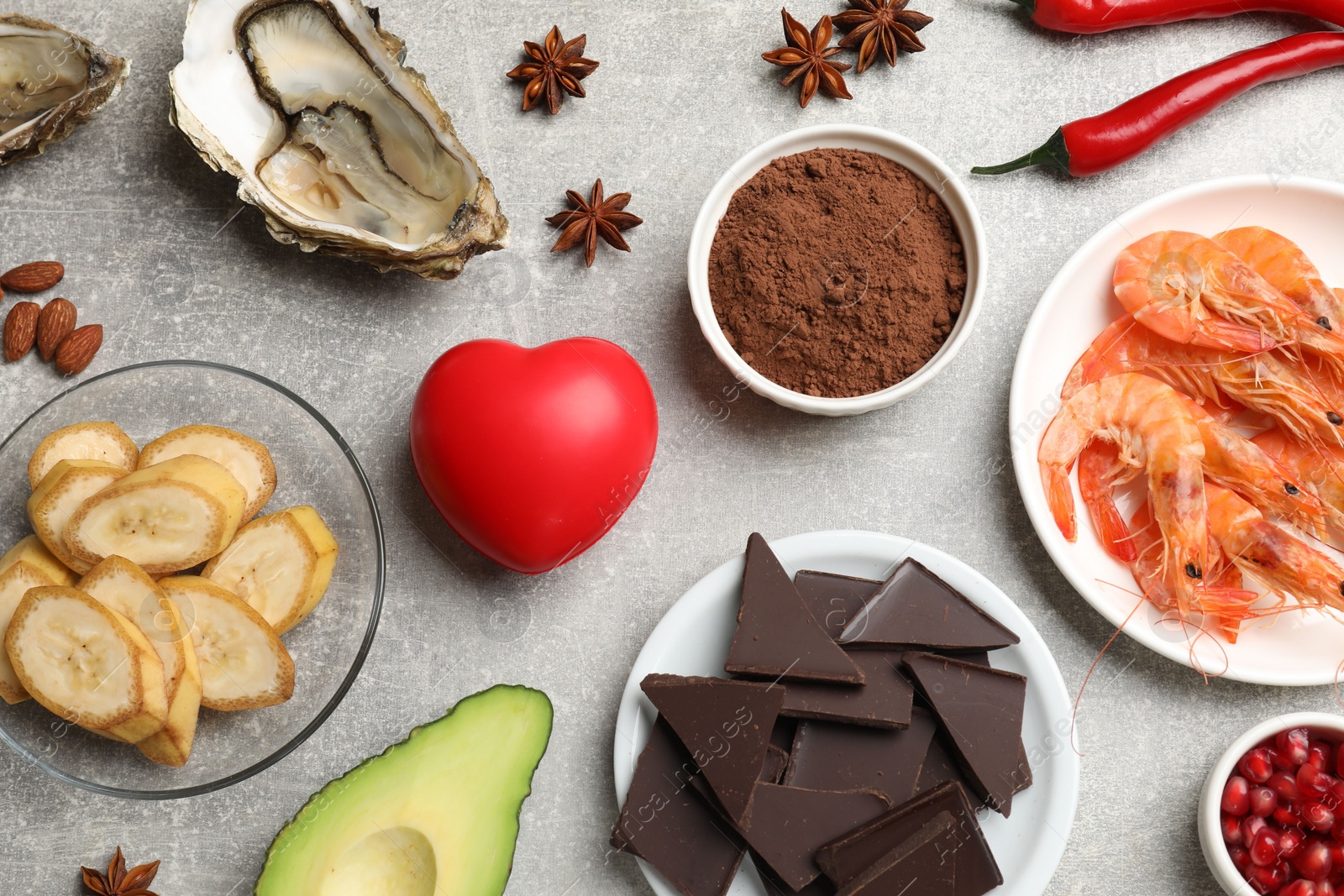 Photo of Natural aphrodisiac. Different food products and heart model on grey table, flat lay