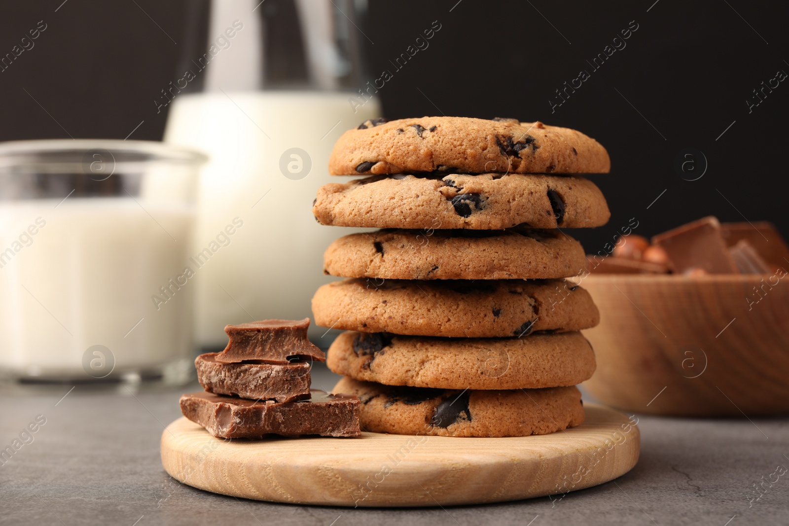 Photo of Stack of delicious chocolate chip cookies and milk on grey table