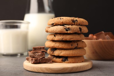 Photo of Stack of delicious chocolate chip cookies and milk on grey table