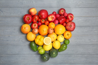 Photo of Heart made of ripe fruits and vegetables in rainbow colors on wooden background, top view