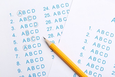 Photo of Orange pencil on answer sheets, top view