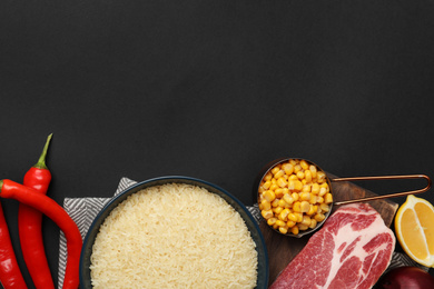 Photo of Flat lay composition with different ingredients on black background, space for text. Risotto recipe