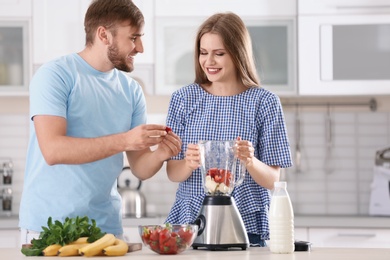 Young couple preparing delicious milk shake in kitchen