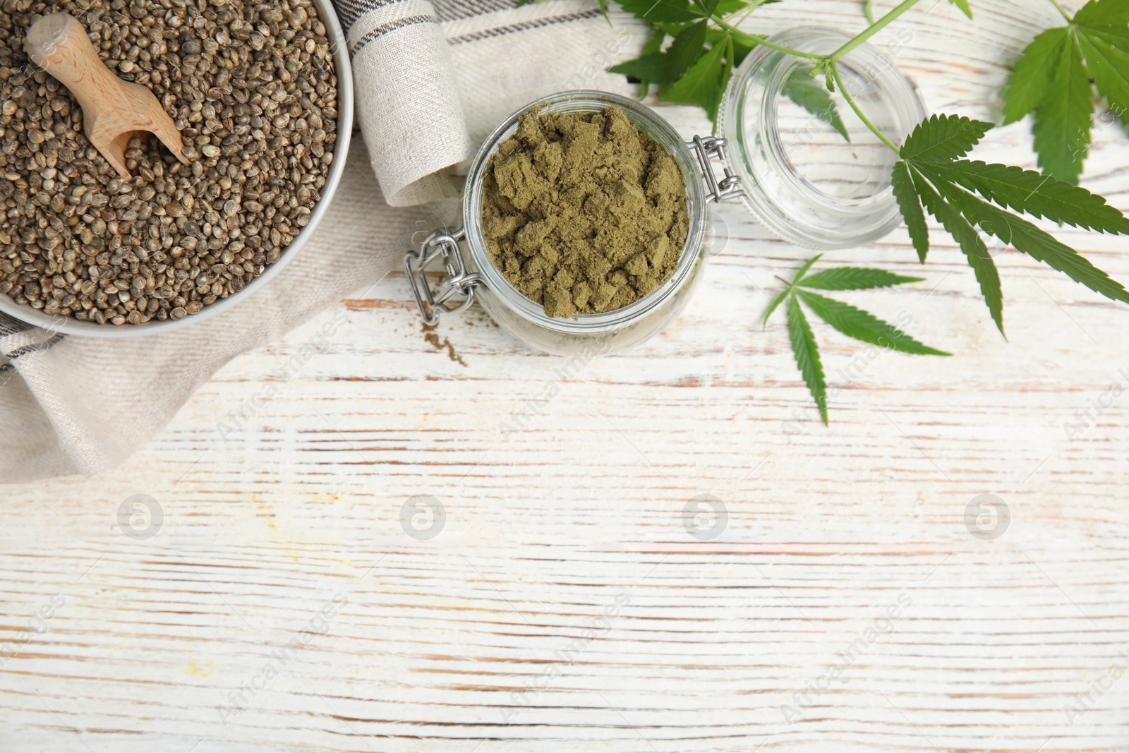 Photo of Hemp protein powder, seeds and fresh leaves on white wooden table, flat lay. Space for text