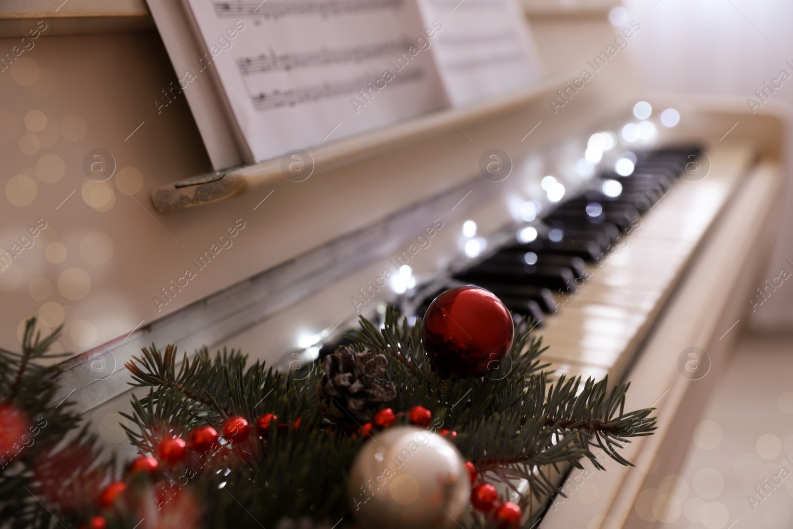 Photo of Fir branches with festive decor on piano keys indoors, space for text. Christmas music