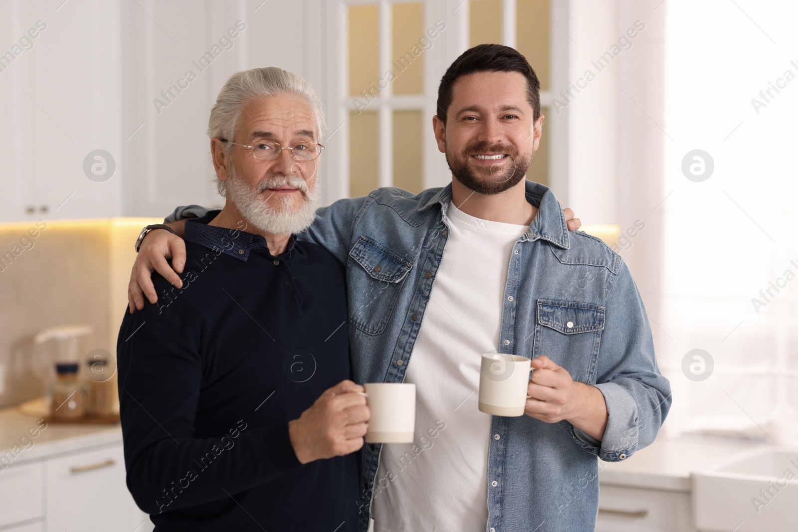 Photo of Happy son and his dad with cups at home