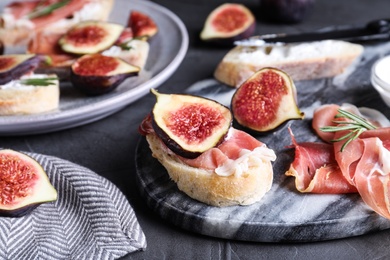Photo of Sandwich with ripe fig, cream cheese and prosciutto served on black table, closeup