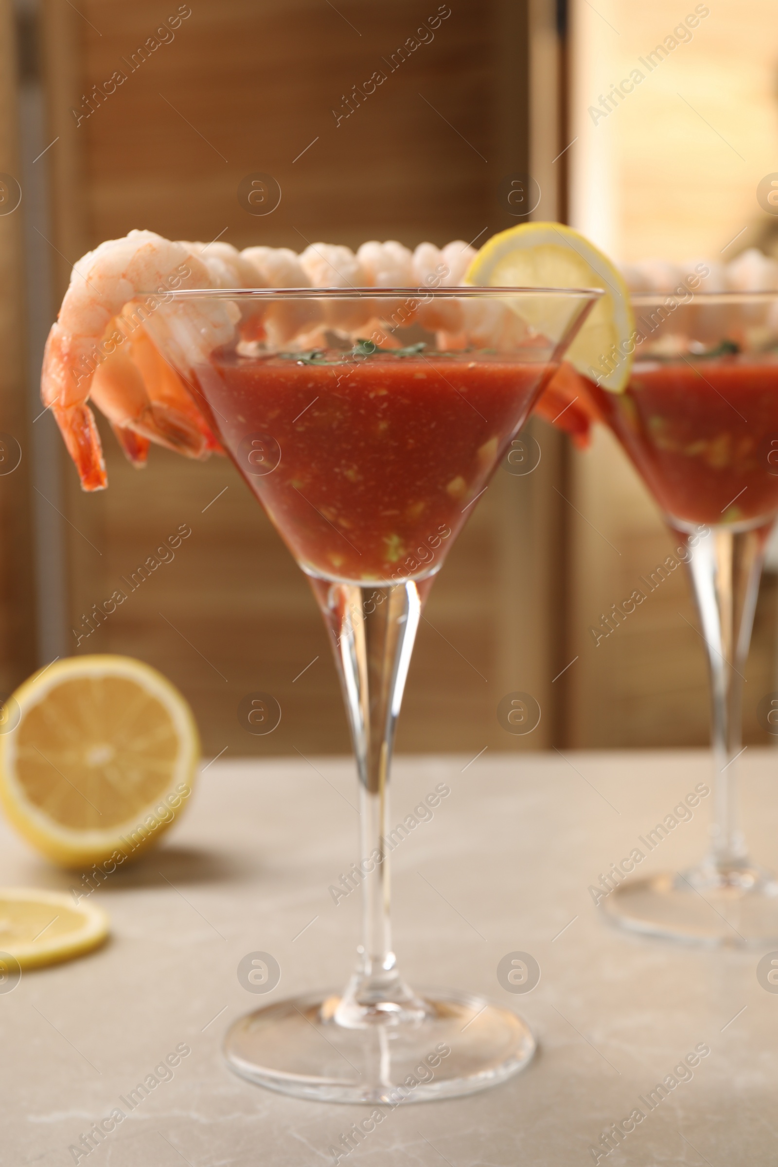 Photo of Tasty shrimp cocktail with sauce in glasses and lemon on light marble table