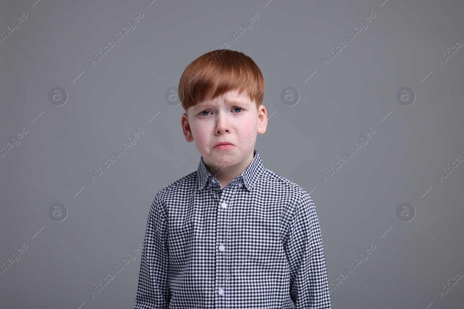 Photo of Portrait of sad little boy on grey background