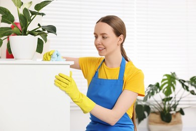 Woman cleaning table with rag at home