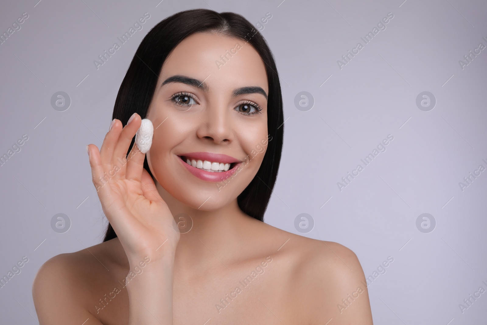 Photo of Woman using silkworm cocoon in skin care routine on light grey background. Space for text