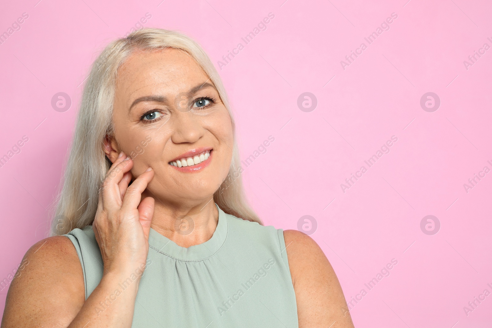 Photo of Portrait of mature woman with beautiful face on pink background. Space for text