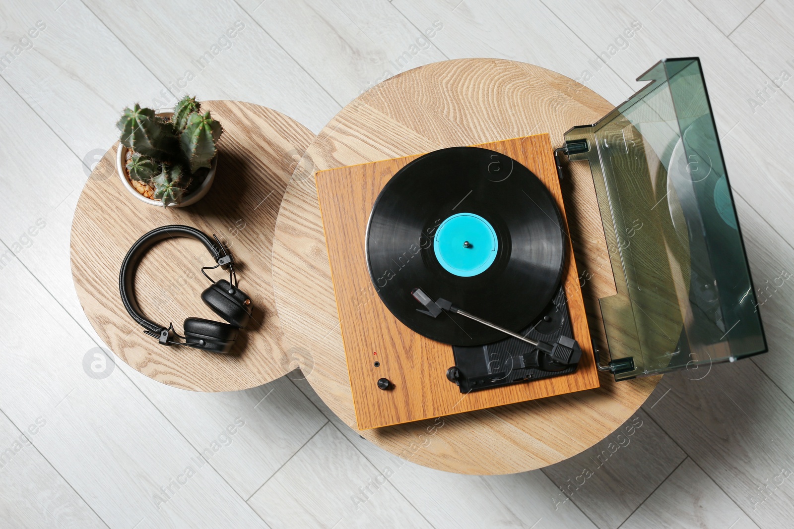 Photo of Stylish turntable with vinyl record, headphones and cactus on wooden table indoors, top view