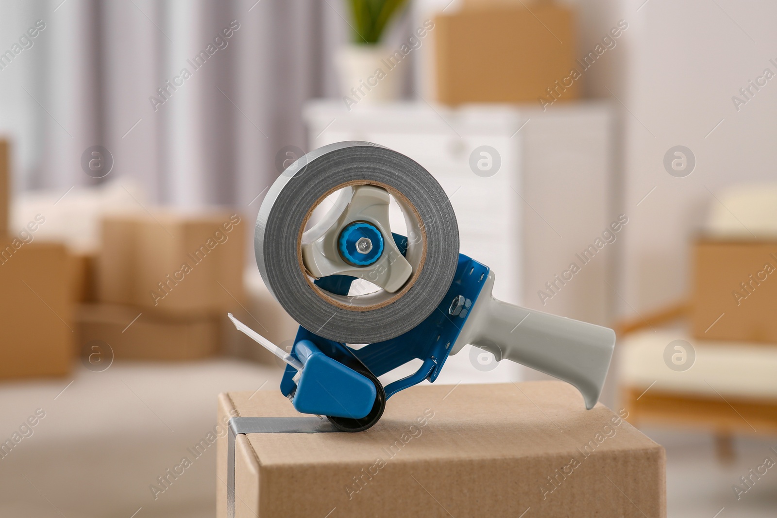 Photo of Dispenser with roll of adhesive tape on box indoors