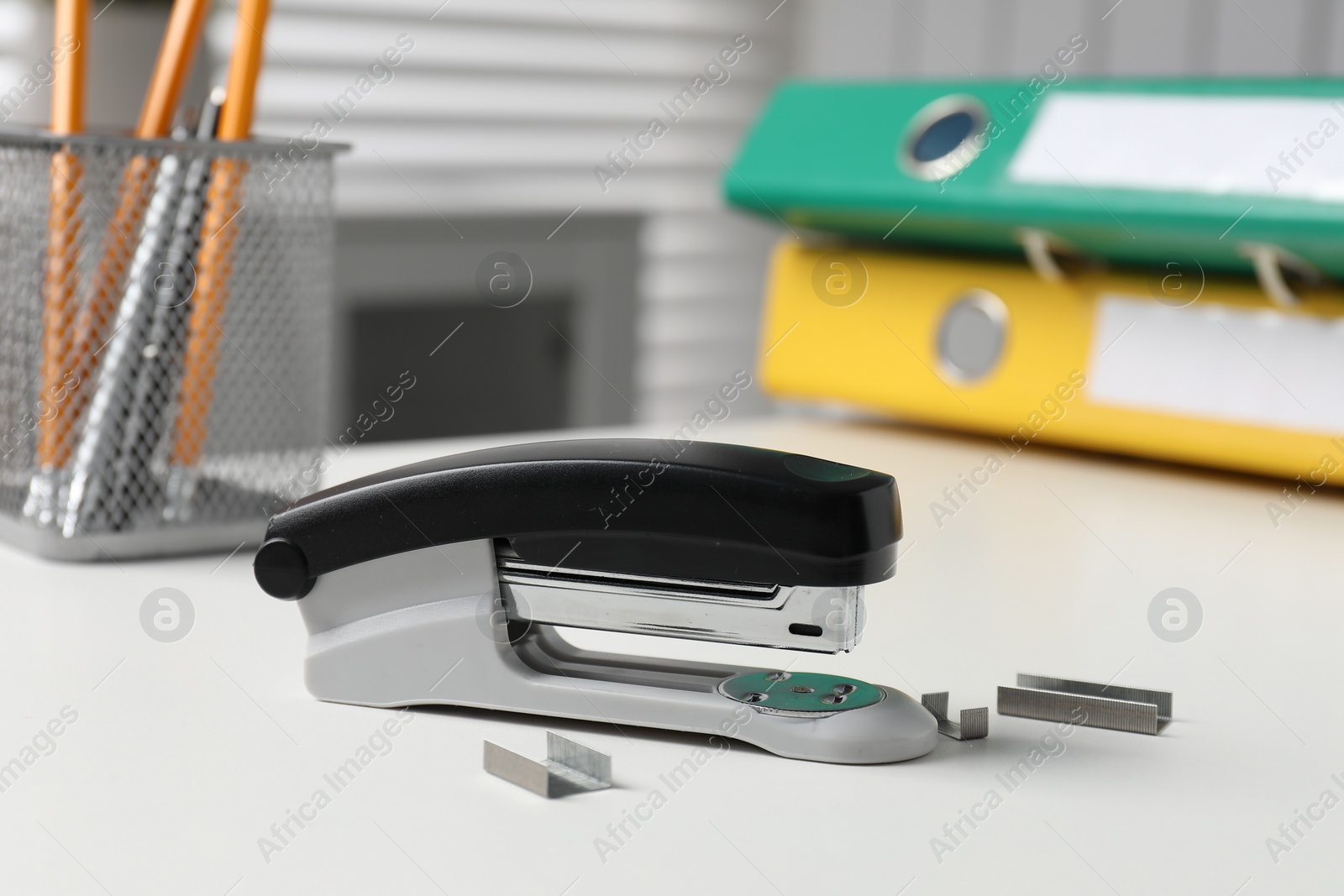 Photo of Stapler and metal staples on white table indoors