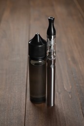 Photo of Electronic cigarette and liquid solution on wooden table