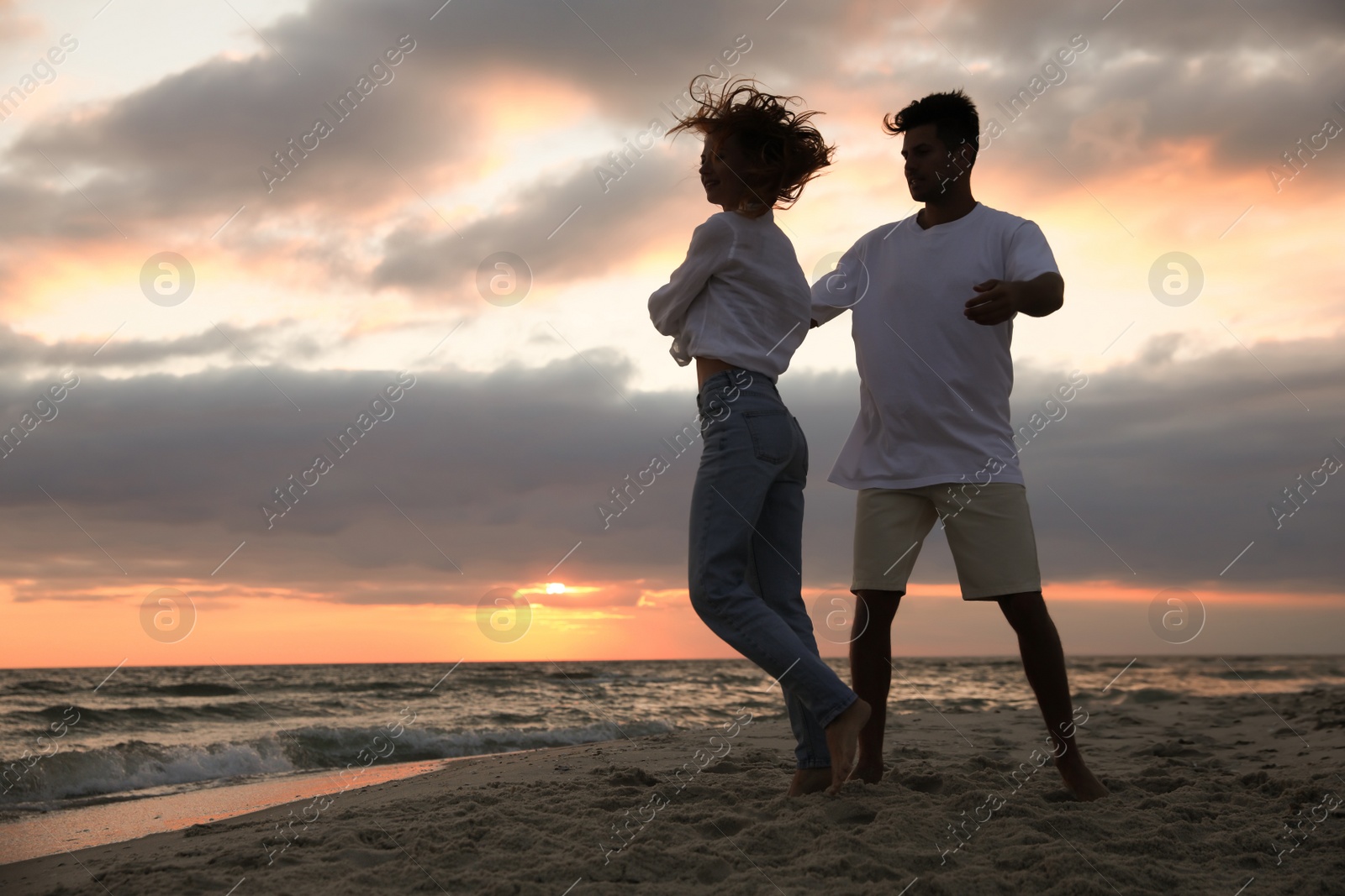 Photo of Happy couple dancing on beach at sunset