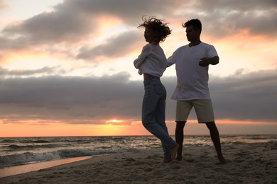 Happy couple dancing on beach at sunset