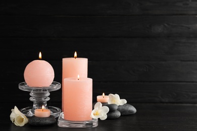 Photo of Composition of burning candles, spa stones and flowers on table. Space for text