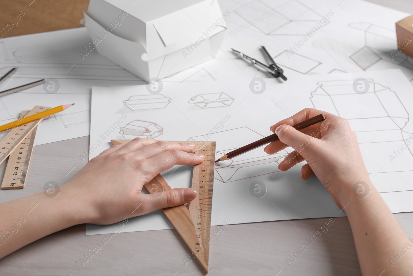 Photo of Woman creating packaging design at light wooden table, closeup