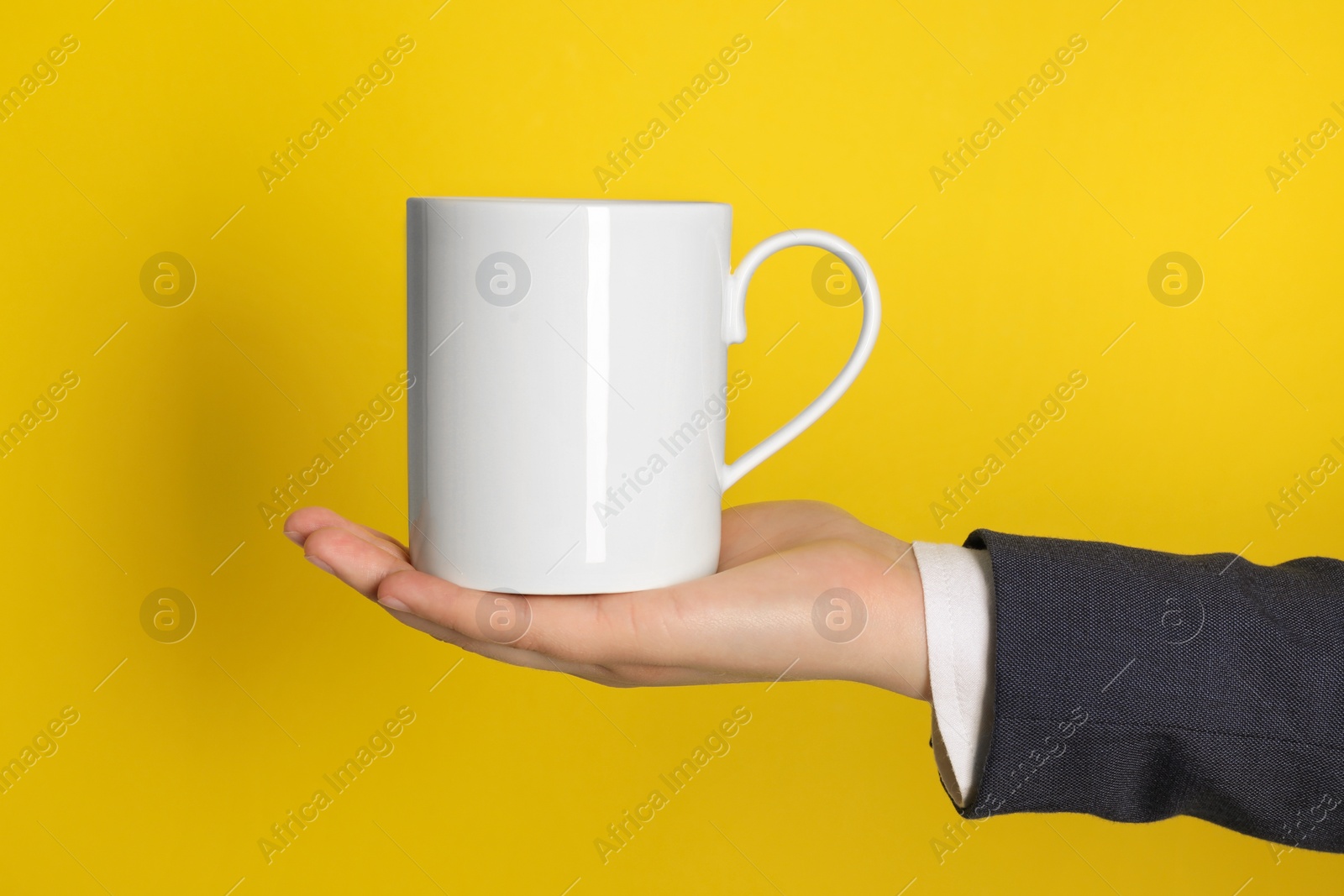 Photo of Woman holding white mug on yellow background, closeup