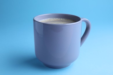 Photo of Mug of freshly brewed hot coffee on light blue background