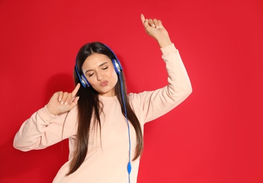 Photo of Attractive young woman enjoying music in headphones on color background. Space for text