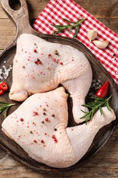 Photo of Raw chicken leg quarters and ingredients on wooden table, flat lay