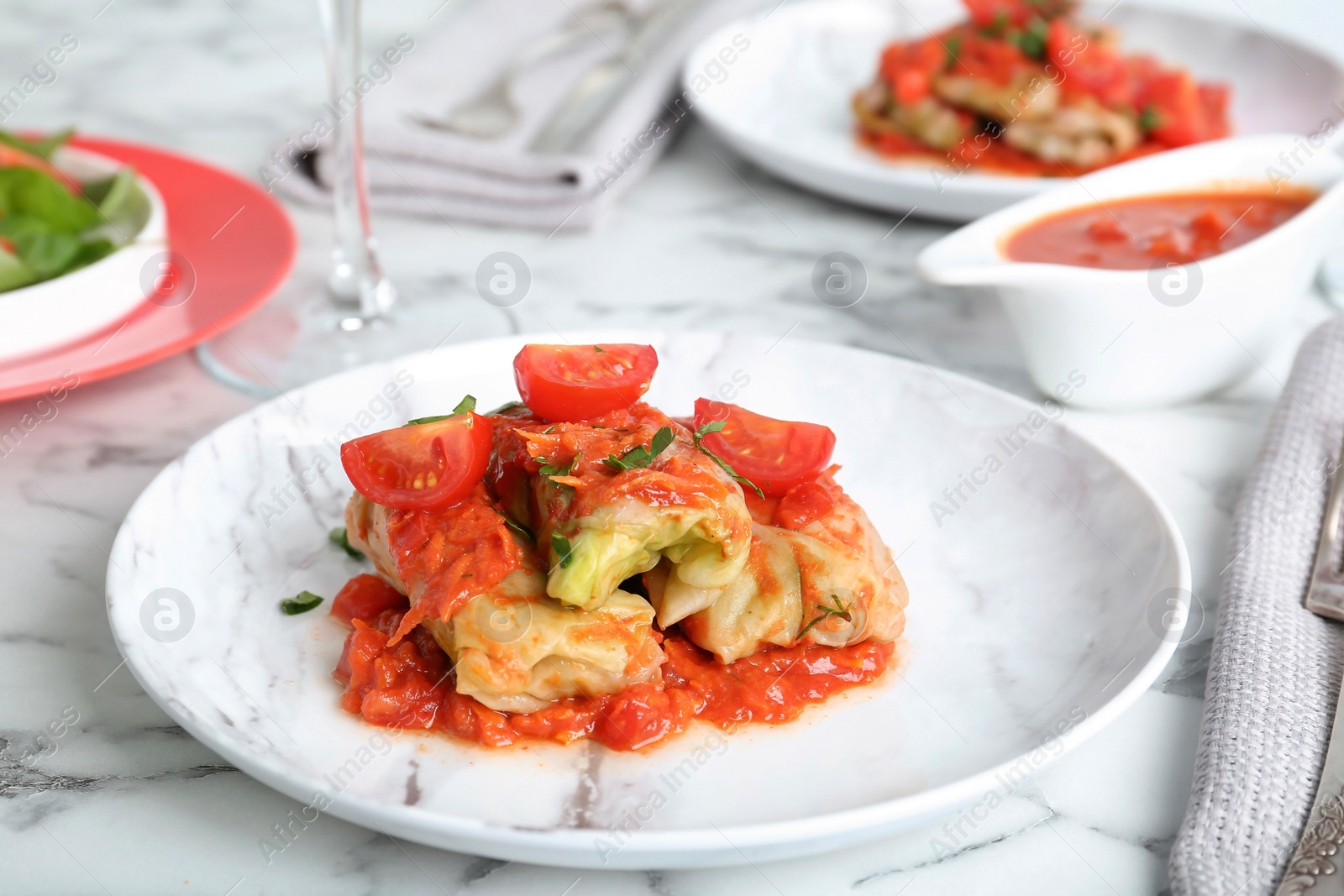 Photo of Plate with stuffed cabbage leaves in tomato sauce on table