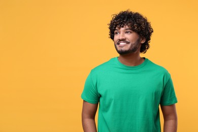 Handsome smiling man on yellow background, space for text