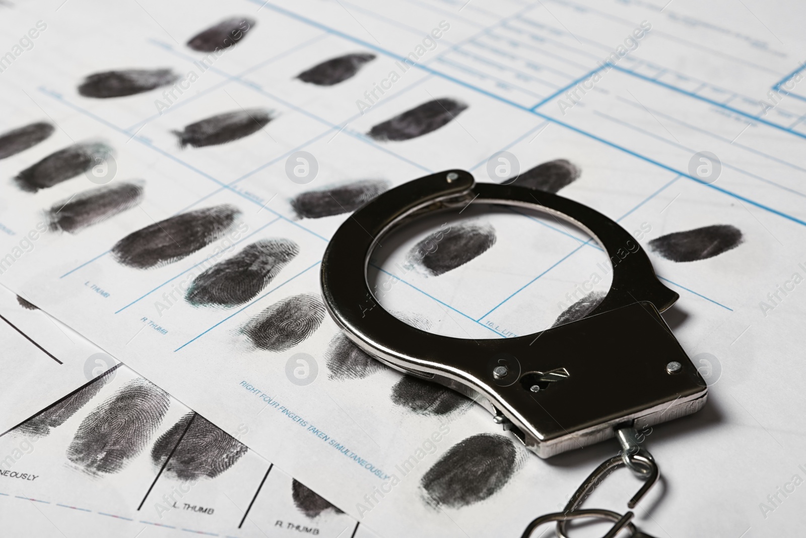 Photo of Police handcuff and criminal fingerprints card, closeup