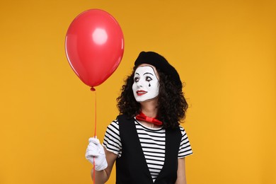 Photo of Funny mine with balloon posing on orange background