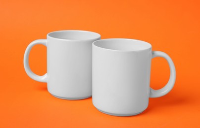 Photo of Two white ceramic mugs on orange background