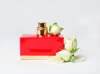 Red bottle of perfume with beautiful flowers on white background