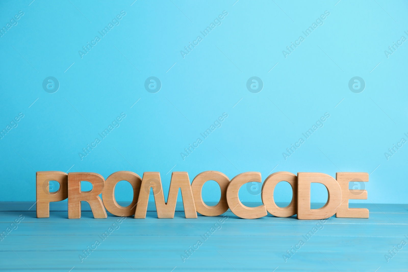 Photo of Words Promo Code made of wooden letters on turquoise table, space for text
