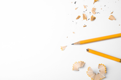 Photo of Broken pencil and shavings on white background, top view