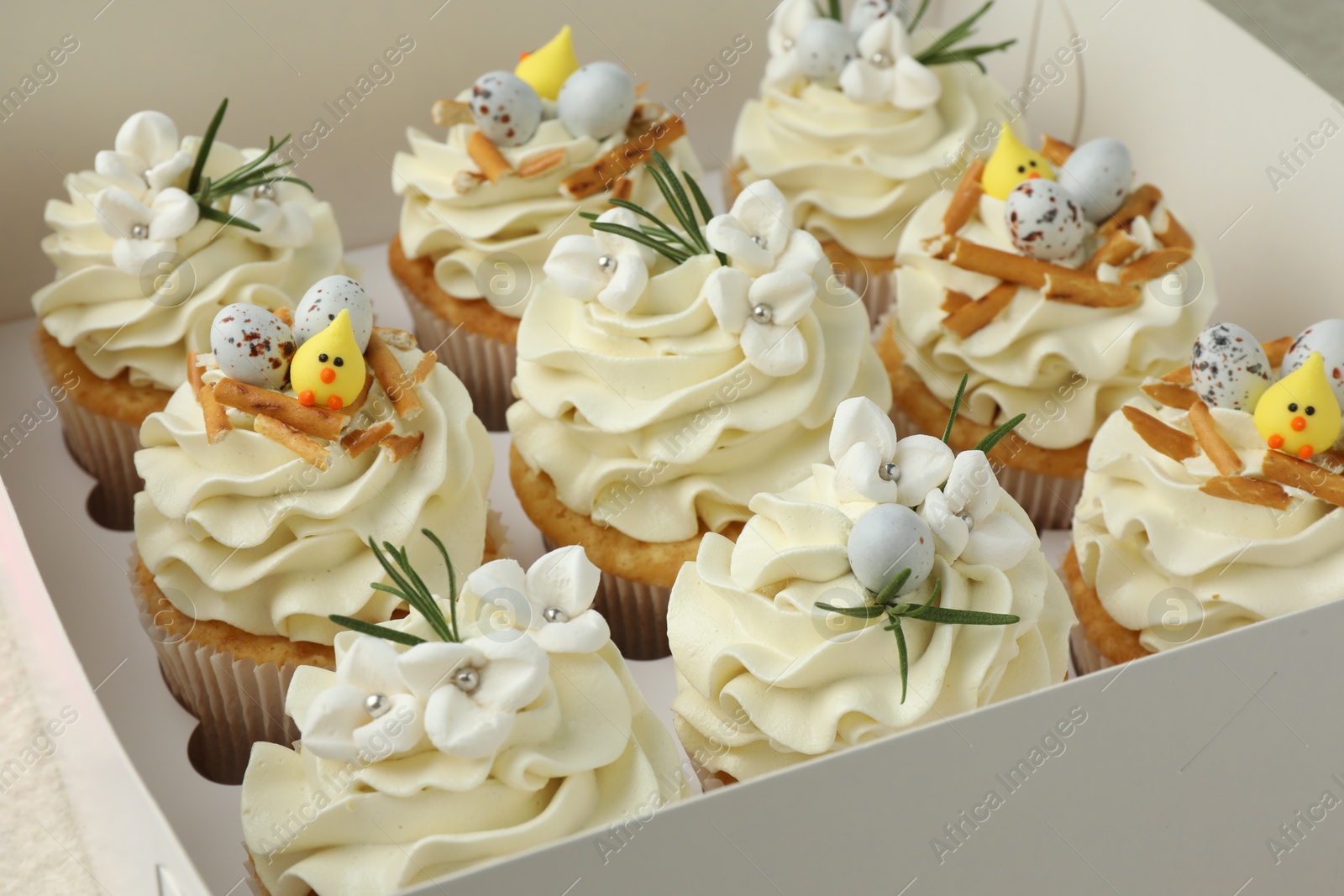 Photo of Tasty Easter cupcakes with vanilla cream in box, closeup