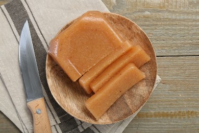 Tasty sweet quince paste and knife on wooden table, top view