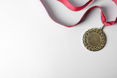 Gold medal with space for design on light background, top view. Victory concept