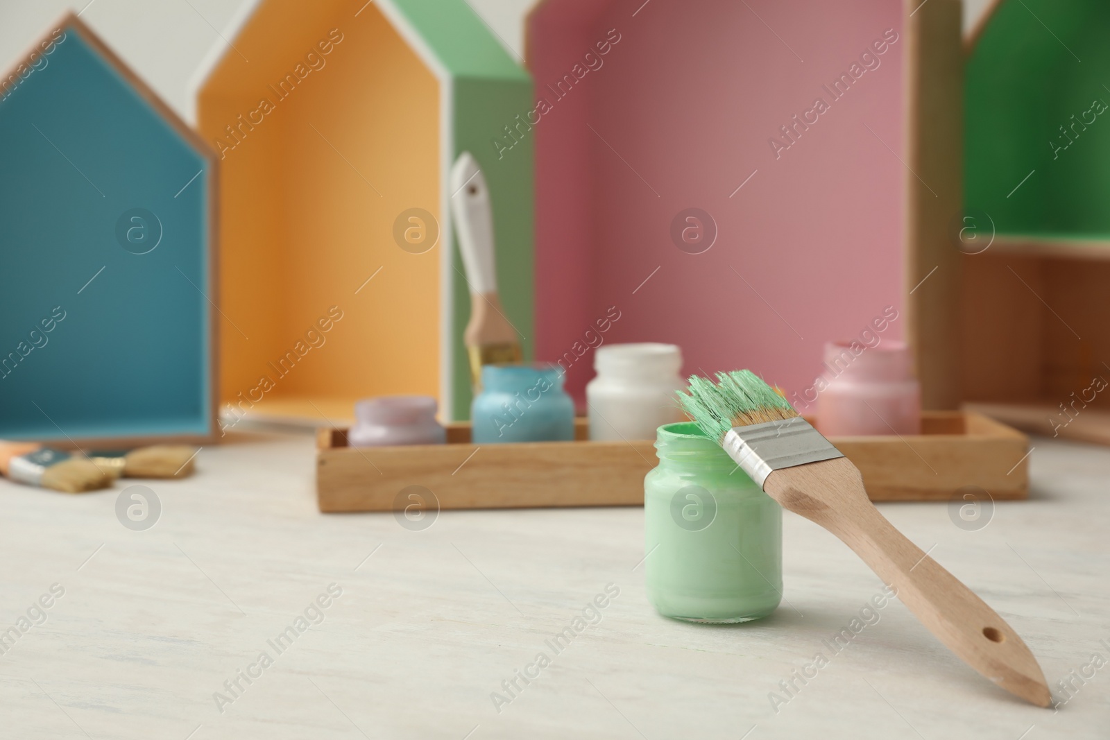 Photo of Jar of green paint and brush on white table. Space for text