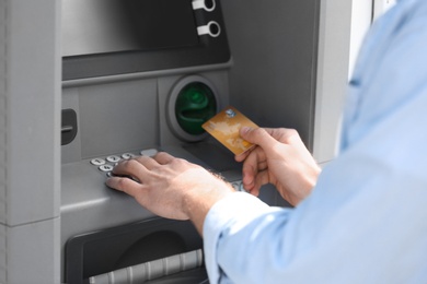 Photo of Man using cash machine for money withdrawal outdoors, closeup