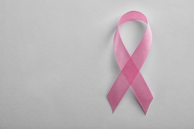 Pink ribbon on white background, top view with space for text. Breast cancer awareness concept