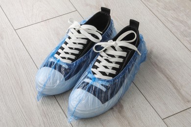 Sneakers in blue shoe covers on light wooden floor