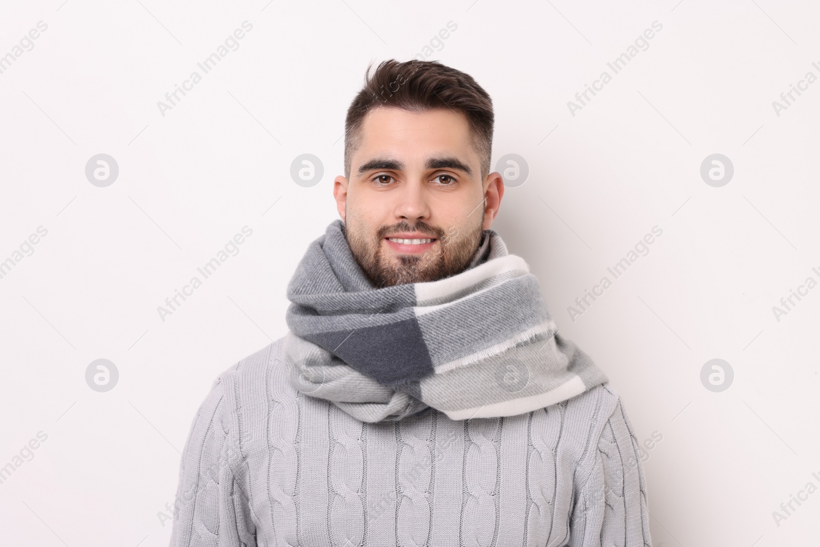 Photo of Portrait of smiling man in warm scarf on light background