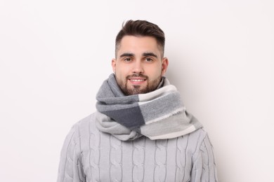 Portrait of smiling man in warm scarf on light background