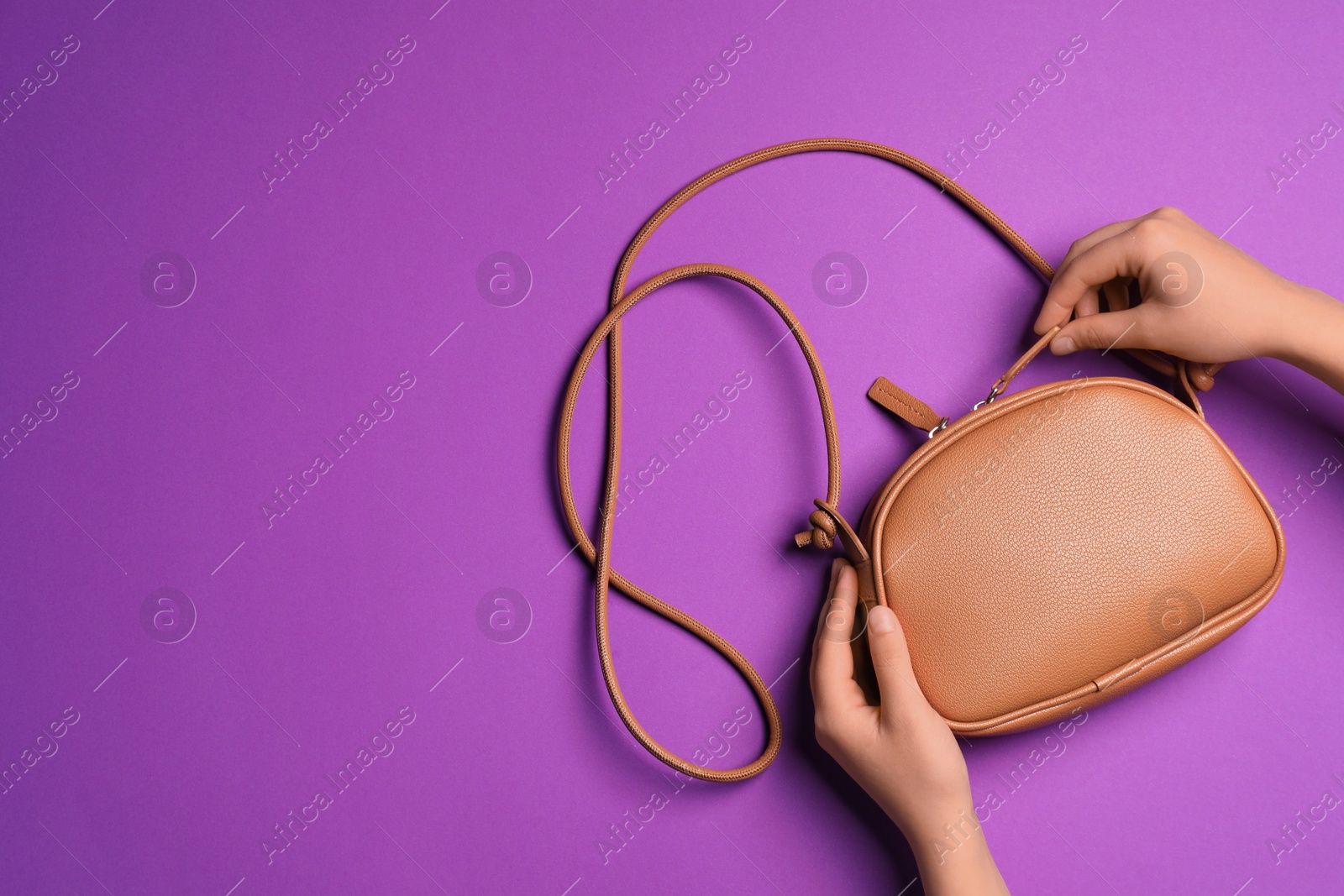 Photo of Woman with stylish bag on violet background, top view. Space for text